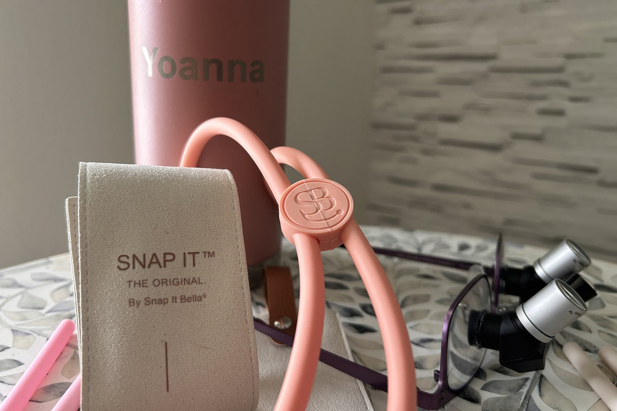 A coral Snap It with the S·B clasp, its suede pouch and a pair of loupes on a stone countertop