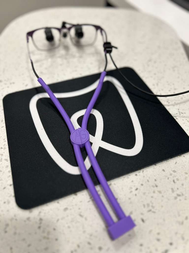 An early purple Snap It clipped to a pair of loupes, the AG monogram on the clasp