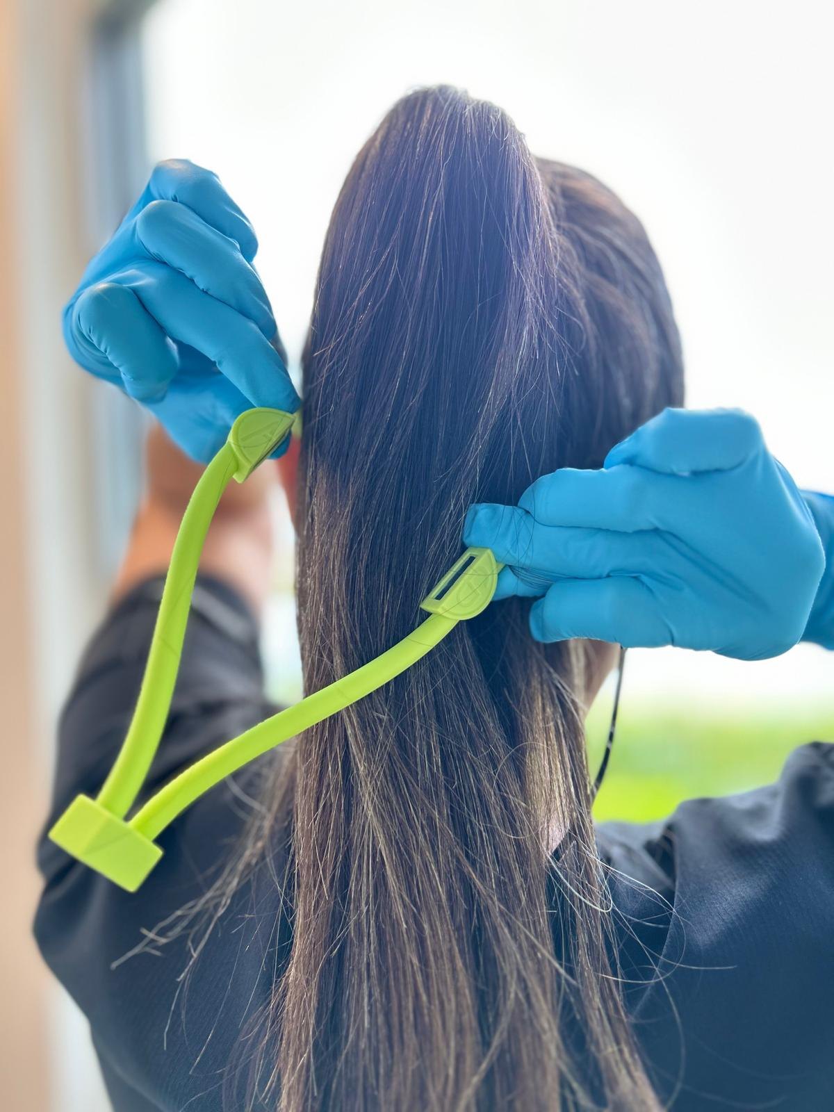 Two gloved hands pulling the magnetic clasp apart behind the head