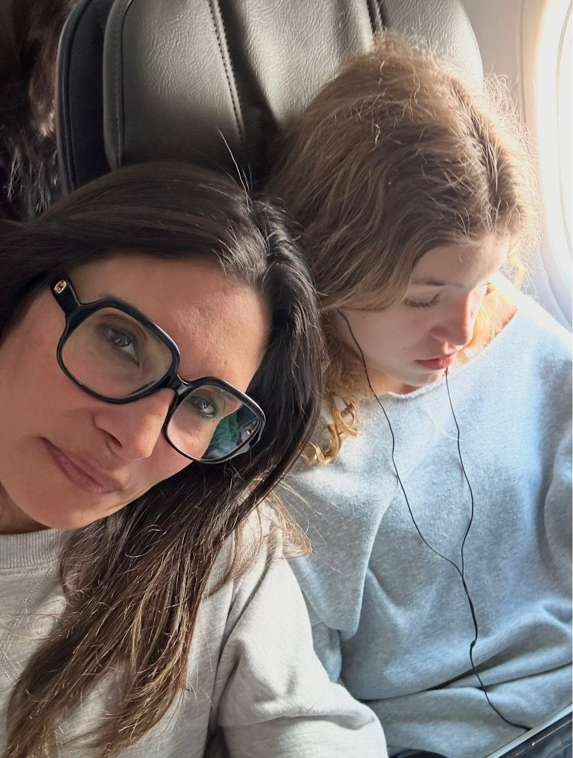 Mother and daughter resting side by side on the plane