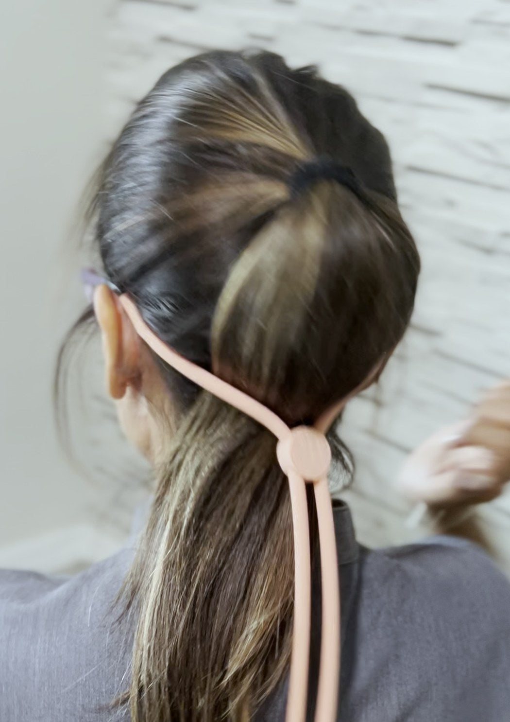Back view with the hair in a ponytail: Snap It runs behind the head and the clasp sits at the nape